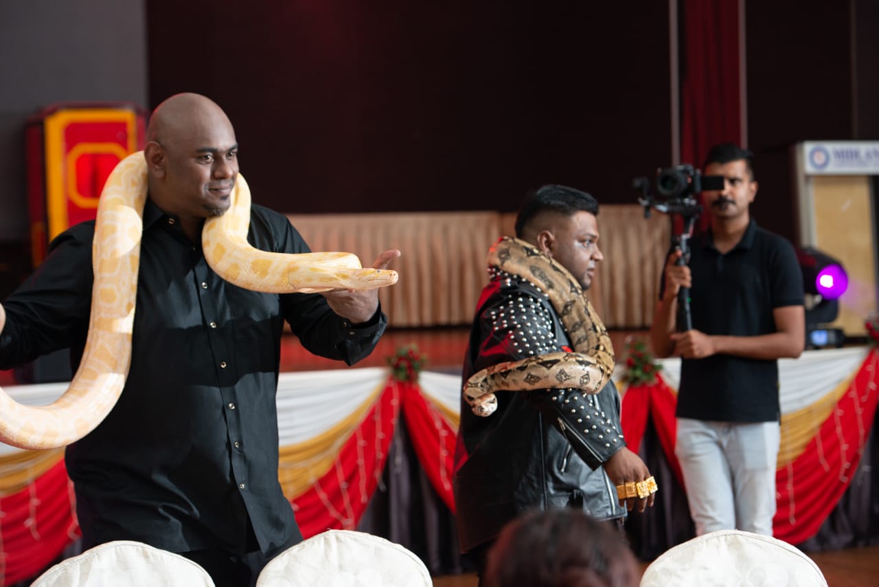 Silan Magician performing a live giant python flash appearance illusion on stage in Malaysia